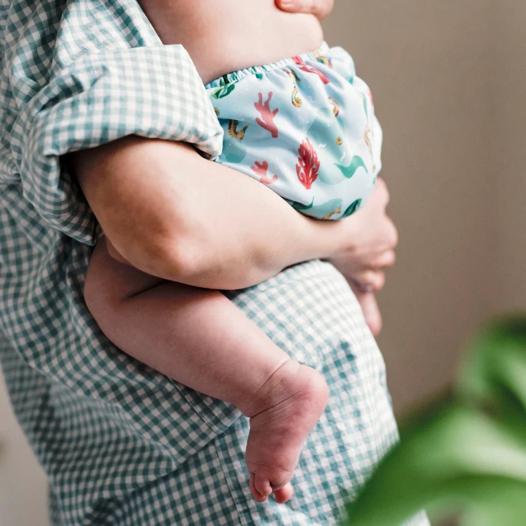 Baby in de armen van mama met wasbaar oefenbroekje met zeedieren