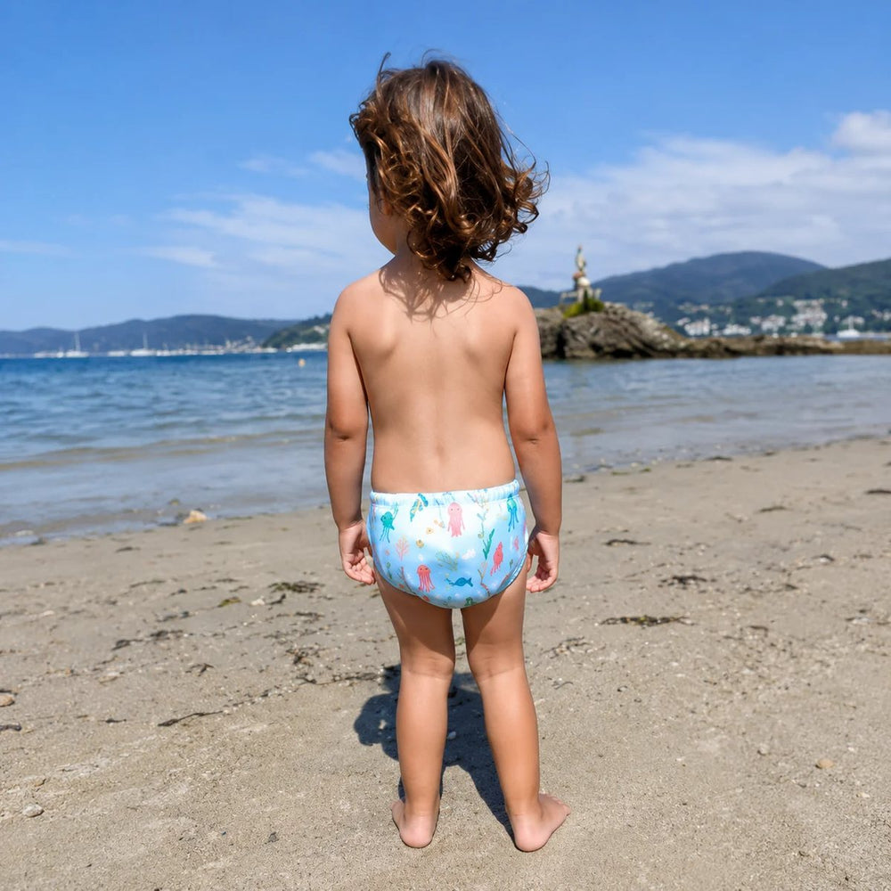 Meisje op het strand met wasbare zwemluier met kwallen